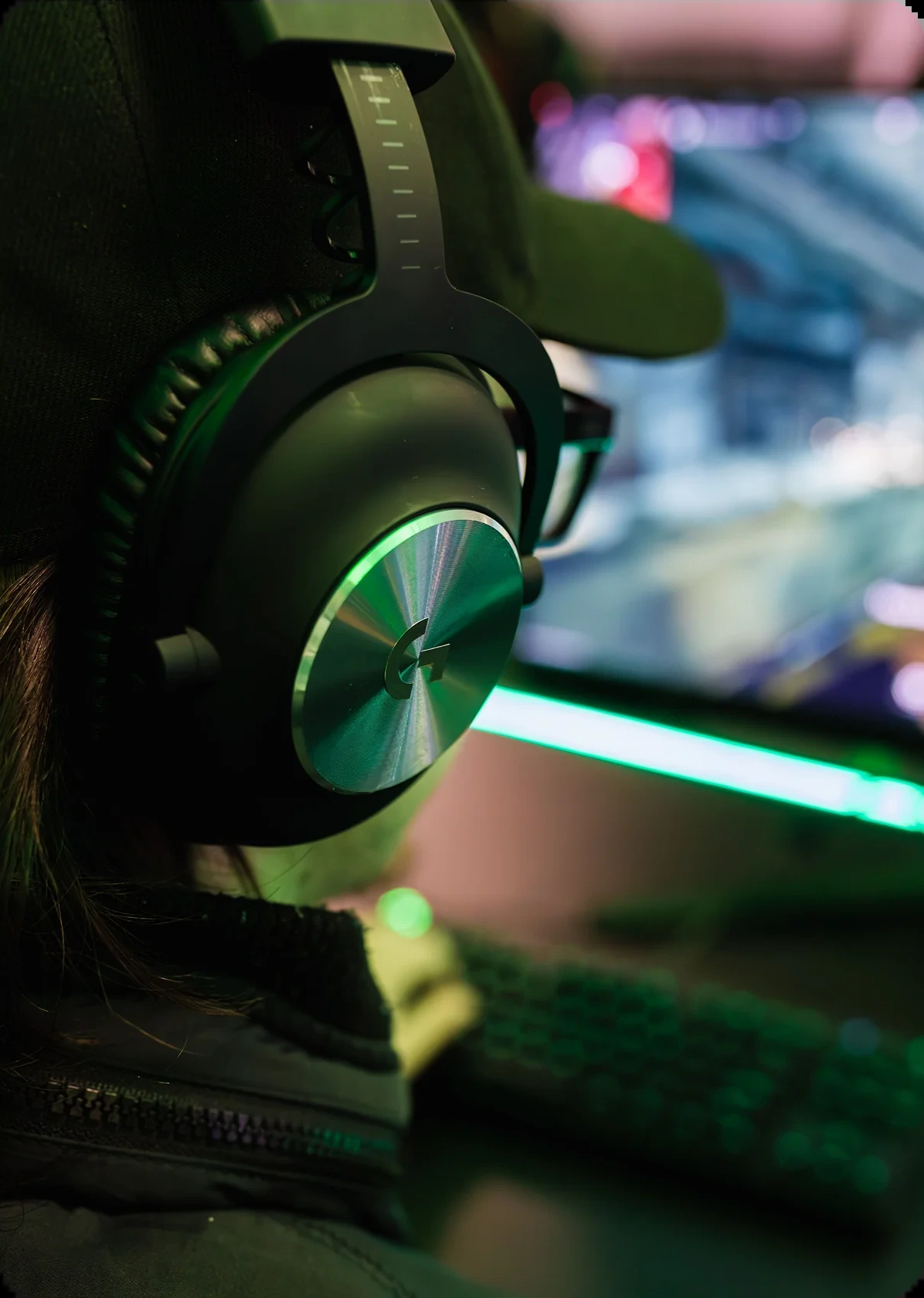 A player wearing a green gaming headset at a backlit keyboard